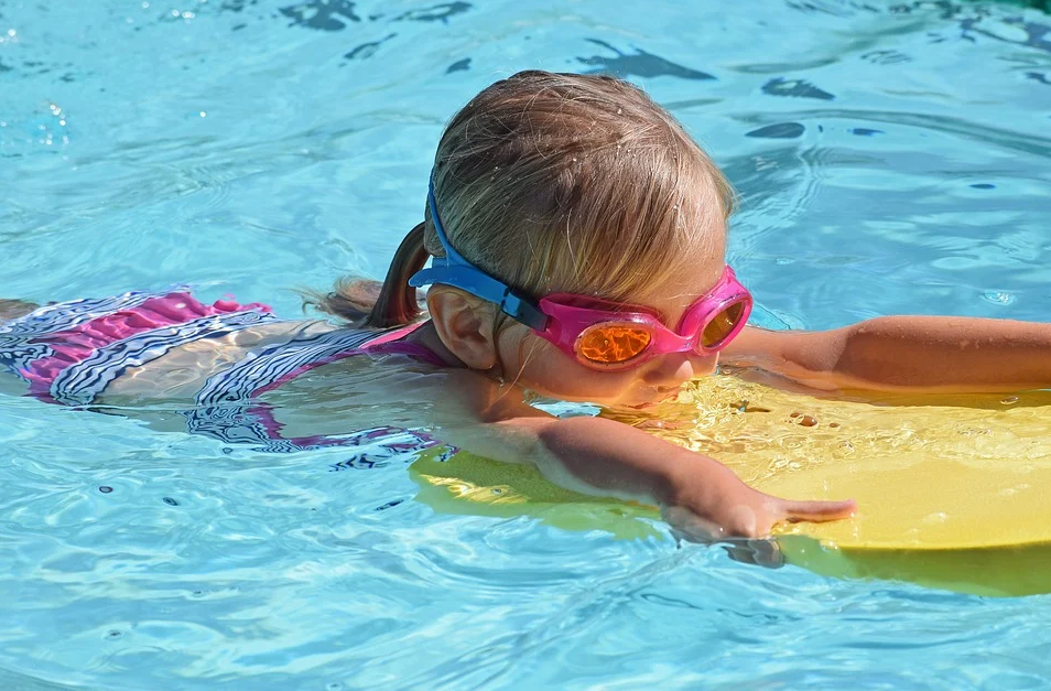 dziecko z okularami do pływania na oczach pływa w basenie