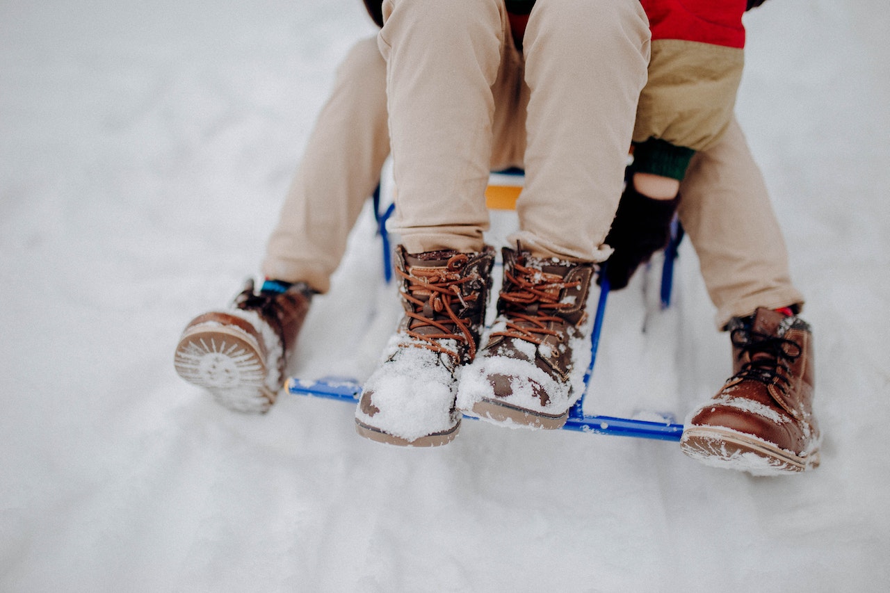 Dzieci mają na sobie buty zimowe jadąc na sankach